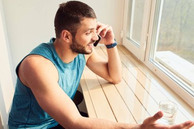 Yakışıklı genç adam evde telefonla konuşuyor.