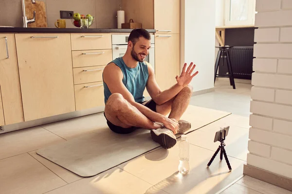 Alegre instructor de gimnasio comunicándose con los clientes en línea desde casa — Foto de Stock