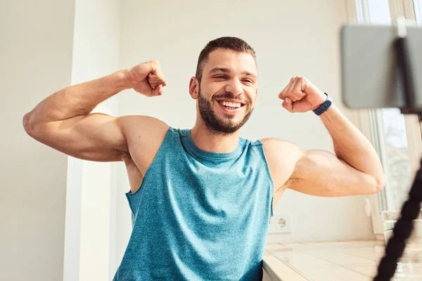 Stilig ung man som visar biceps muskler och ler — Stockfoto