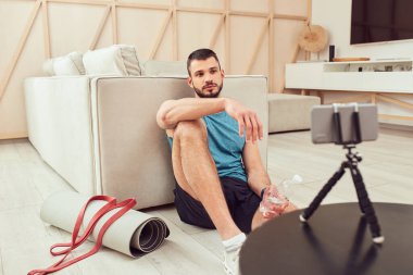 Akıllı telefondan online antrenman izleyen yakışıklı bir beyefendi.