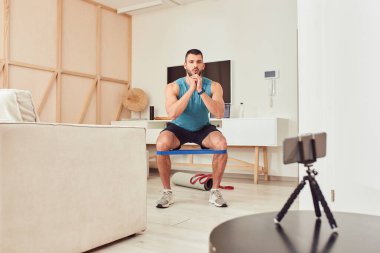 Atletik genç adam elastik fitness bandıyla egzersiz yapıyor.