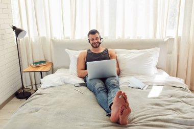 Yatak odasında modern defter kullanan neşeli bir beyefendi.