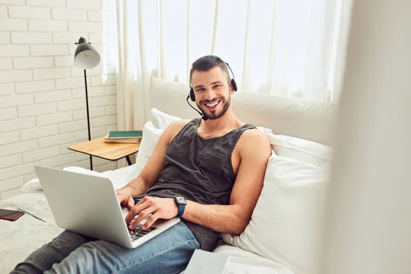 Vidám fiatalember használja laptop a hálószobában — Stock Fotó