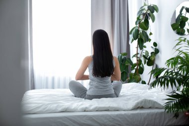 Hafif yatak odasında meditasyon yapan ince bir kadın.