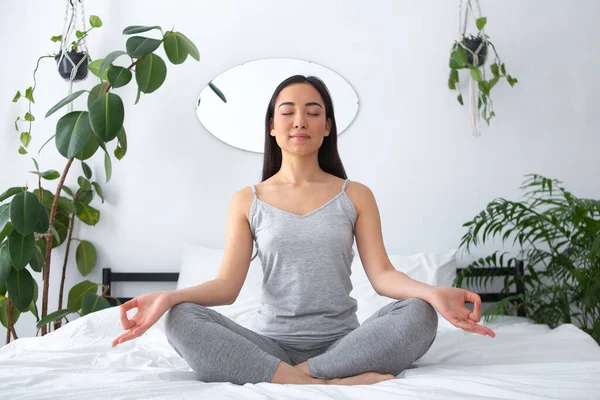 Smiling young pretty woman meditating in bedroom — Stockfoto