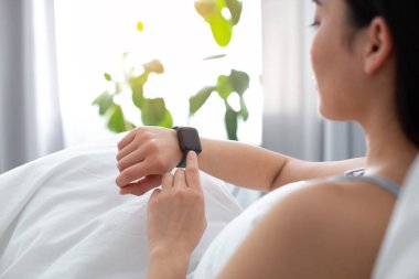 Yatakta kalırken takip cihazı kullanan bir kadın