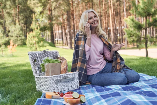 Счастливая красавица разговаривает по смартфону во время пикника — стоковое фото
