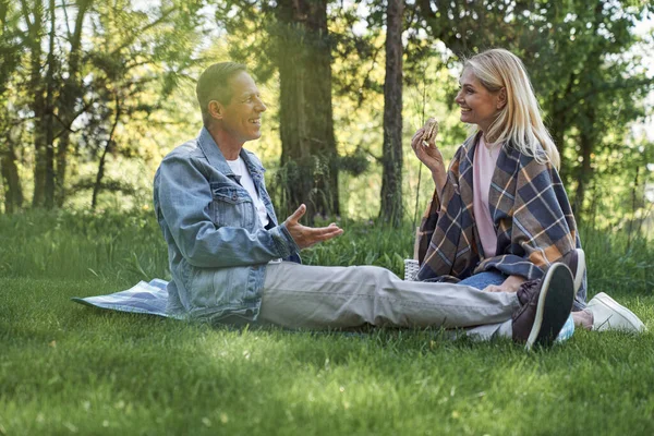 Gelukkige paar praten tijdens picknick in het bos — Stockfoto