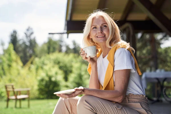 Cheerful mature woman enjoying hot drink outdoors — Stock Photo, Image