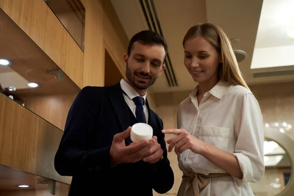 Dois jovens olhando para o pote de creme e sorrindo — Fotografia de Stock