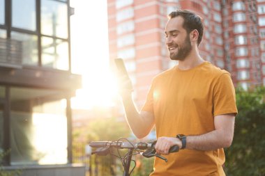 Neşeli genç adam açık havada telefonla aktif bir gün geçiriyor.