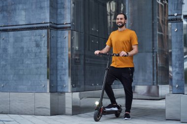 Neşeli yakışıklı adam şehirde çevreci aracı kullanıyor.