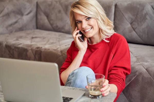 Boldog fiatal nő pihen otthon, és élvezi a telefonbeszélgetést — Stock Fotó