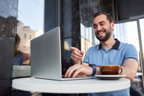 Homem alegre assistindo vídeo no laptop ao ar livre — Fotografia de Stock