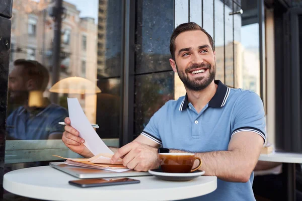 Jolly empresario que trabaja con gadgets y papeles en la cafetería —  Fotos de Stock