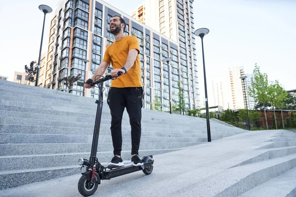 Gelukkig jongeman rijden aangedreven scooter in de stad — Stockfoto