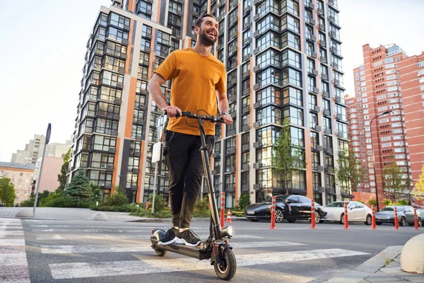 Счастливый бородатый человек, путешествующий по городу на скутере — стоковое фото