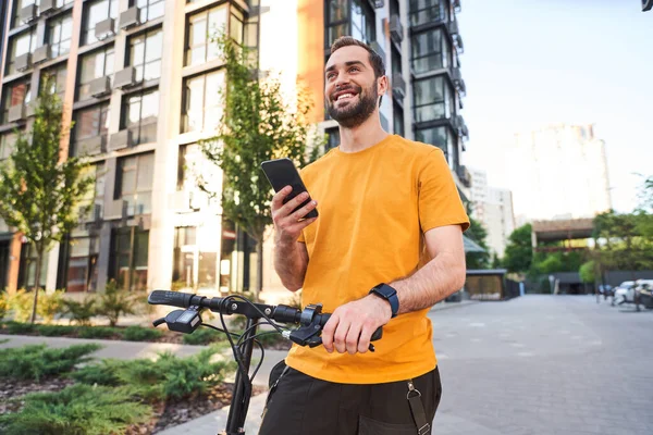 Веселый молодой человек со смартфоном на скутере — стоковое фото