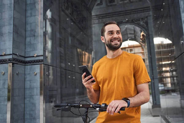 Jovem alegre com telefone celular em scooter — Fotografia de Stock