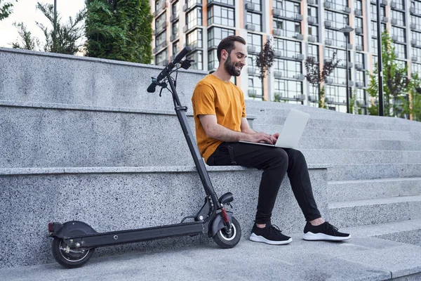 Gelukkig man met aangedreven scooter en notebook — Stockfoto