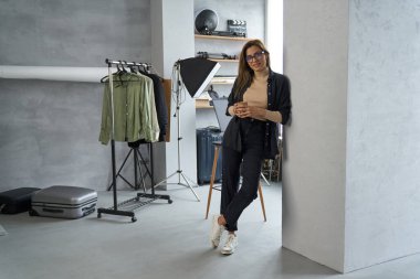 Sanat atölyesinde kahve içen rahat genç bir kadın.