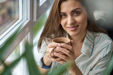 Kapalı mekanda çay fincanı olan mutlu güzel bir kadın.