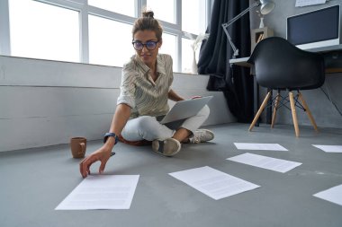 Evde defter ve kağıtlarla çalışan mutlu bir kadın.