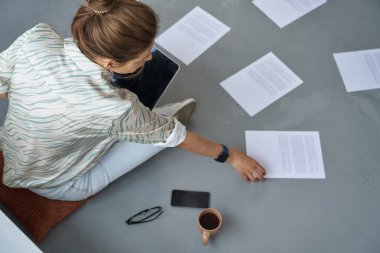 Kadın içeride dizüstü bilgisayarla evrak işi yapıyor.