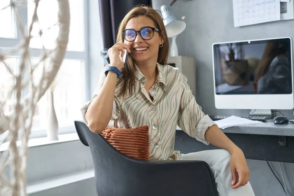 Mujer joven y feliz hablando en el teléfono inteligente en interiores — Foto de Stock