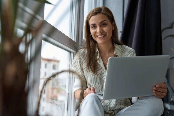 Ευτυχισμένη ελκυστική γυναίκα που χρησιμοποιεί φορητό υπολογιστή στο σπίτι — Φωτογραφία Αρχείου