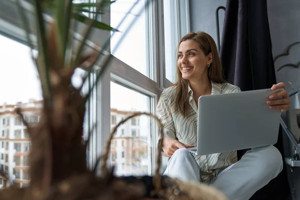 Mujer feliz con portátil en el apartamento de la ciudad — Foto de Stock