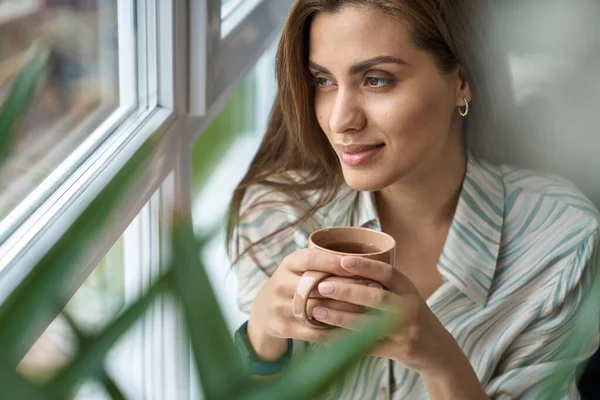Kapalı alanda çay fincanı ile gülümseyen güzel bayan.