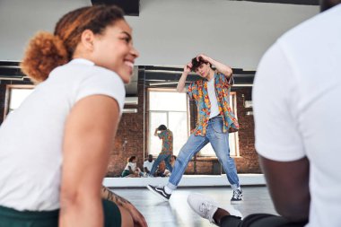 Genç kıvırcık çocuk arkadaşlarıyla spor stüdyosunda.