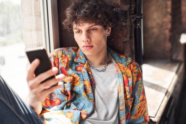 Yakışıklı genç adam kapalı alanda akıllı telefon kullanıyor.