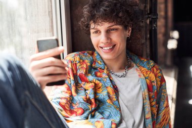 Gülümseyen adam akıllı telefon ekranına bakıyor.