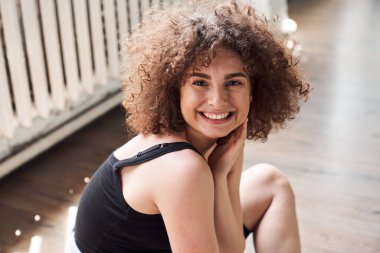 Gülümseyen güzel kadın dans stüdyosunda yerde oturuyor.