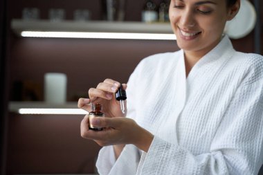 Elinde bir kavanoz deri yağı tutan gülümseyen kadın.