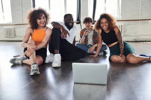 Mutlu arkadaşlar dans stüdyosunda yerde oturuyor.