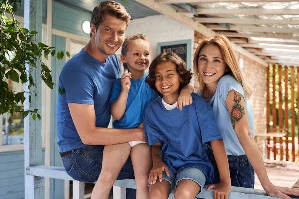 Счастливая семья обнимается и улыбается снаружи дома — стоковое фото