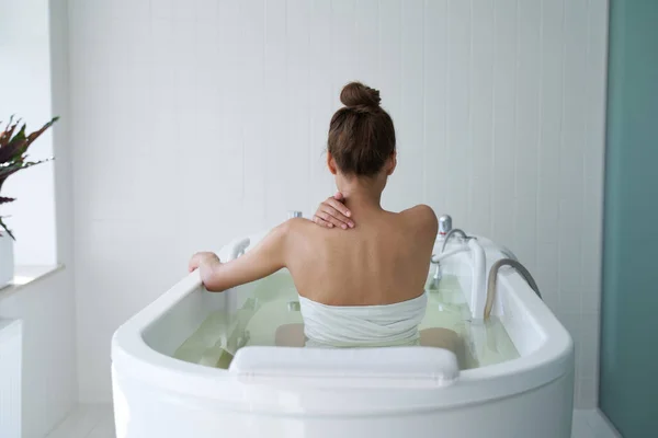 Junge Dame sitzt im Hydrobad während Wellness-Behandlung — Stockfoto