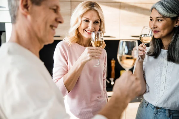 Hombre sonriente y dos mujeres sosteniendo copas de vino — Foto de Stock