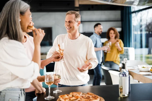 Uomo sorridente che parla con amiche in cucina — Foto Stock