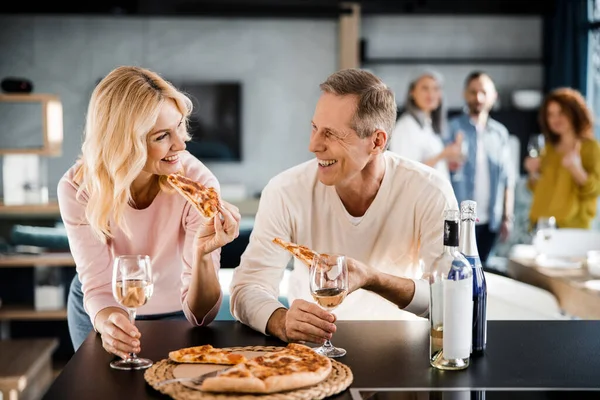 Feliz casal adulto comer pizza na cozinha — Fotografia de Stock