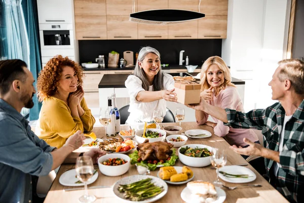 Happy friends are exchanging gifts during thanksgiving