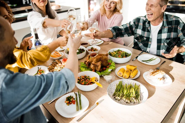 Gelukkig volwassen mannen en vrouwen zitten aan de feestelijke tafel in de woonkamer — Stockfoto