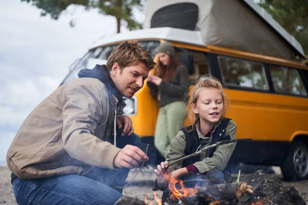 Papa en dochter wakkeren het vuur aan in de natuur — Stockfoto