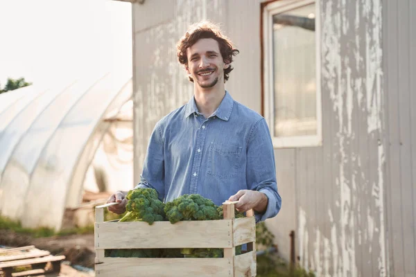 Heureux jeune agriculteur portant boîte de récolte — Photo