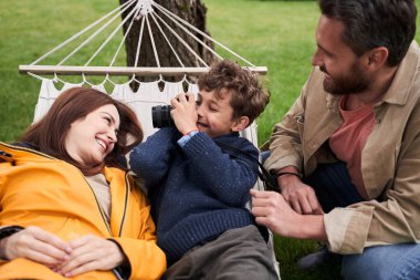 Neşeli çocuk dışarıda ailesiyle vakit geçirirken kamera kullanıyor.