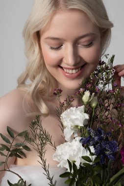 Güzel çiçekleri tutan mükemmel ciltli neşeli genç kadın.