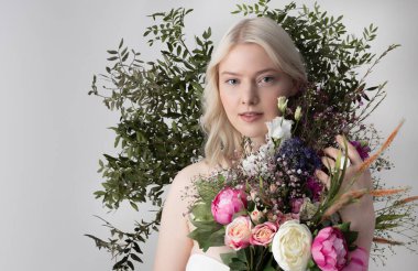 Beyaz arka planda duran çiçekli güzel bayan.